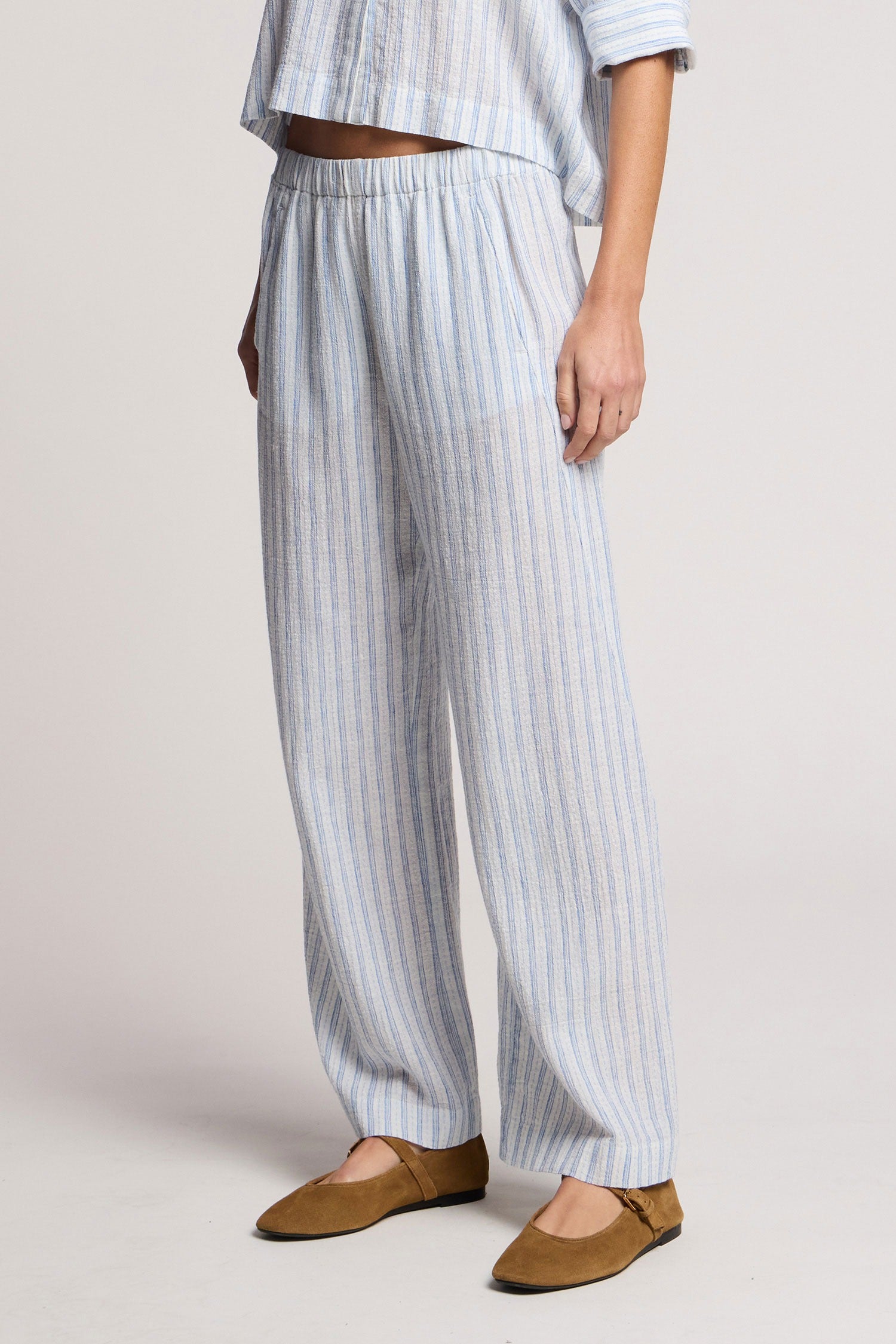 Person wearing light blue and white striped pants with a plain background