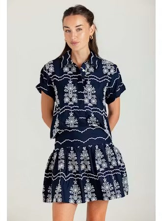 Woman wearing a navy dress with white patterns on a plain background