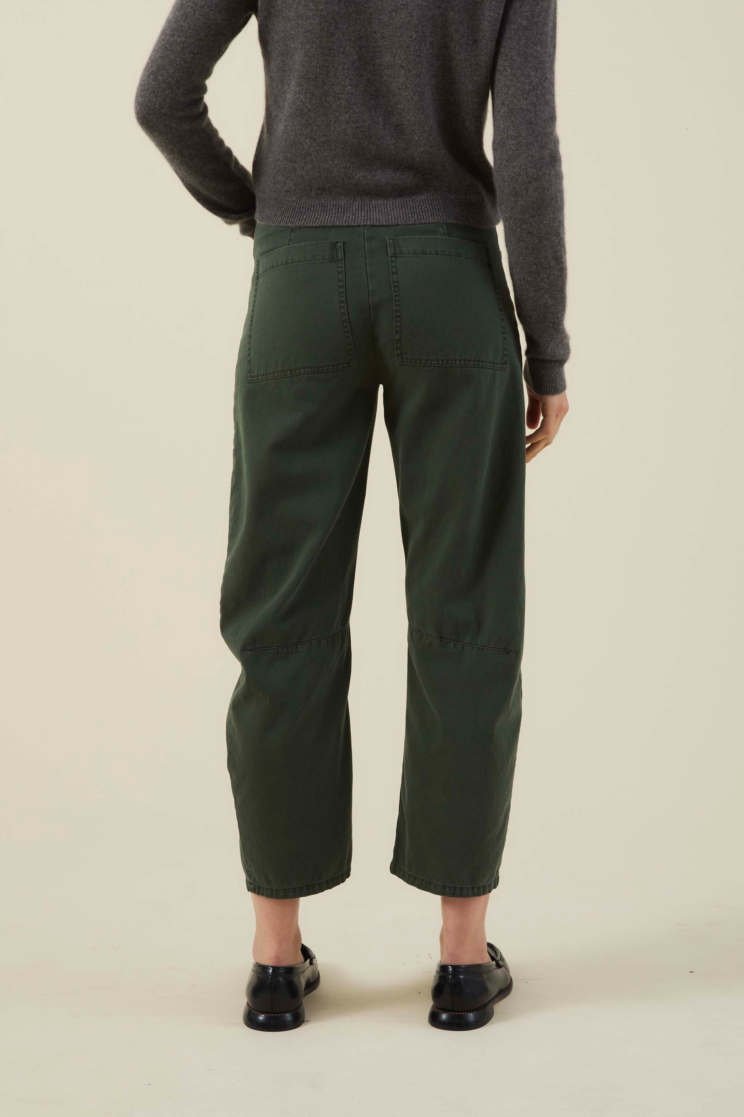 Person wearing green pants and a gray sweater on a beige background