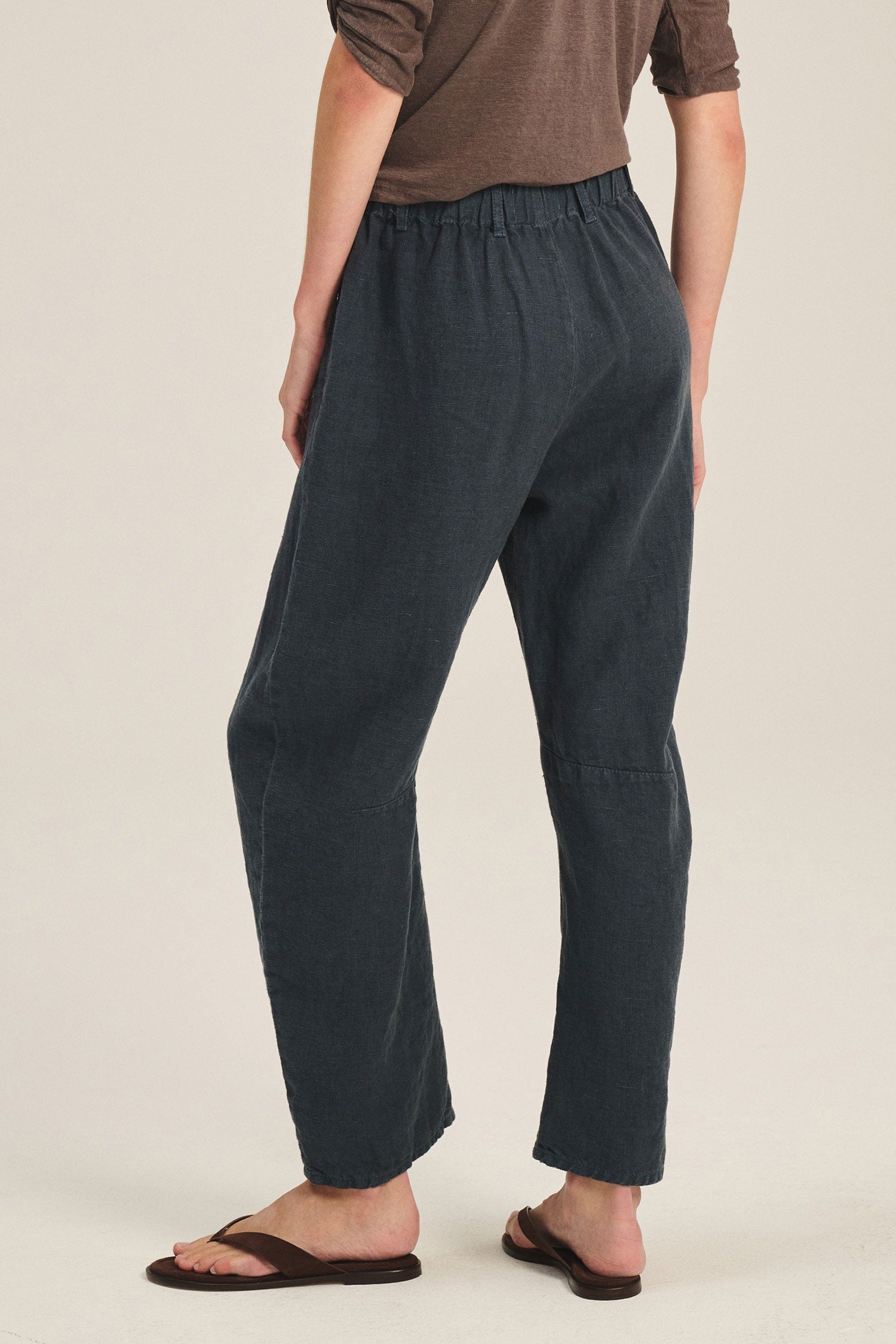 Person wearing dark gray pants on a beige background