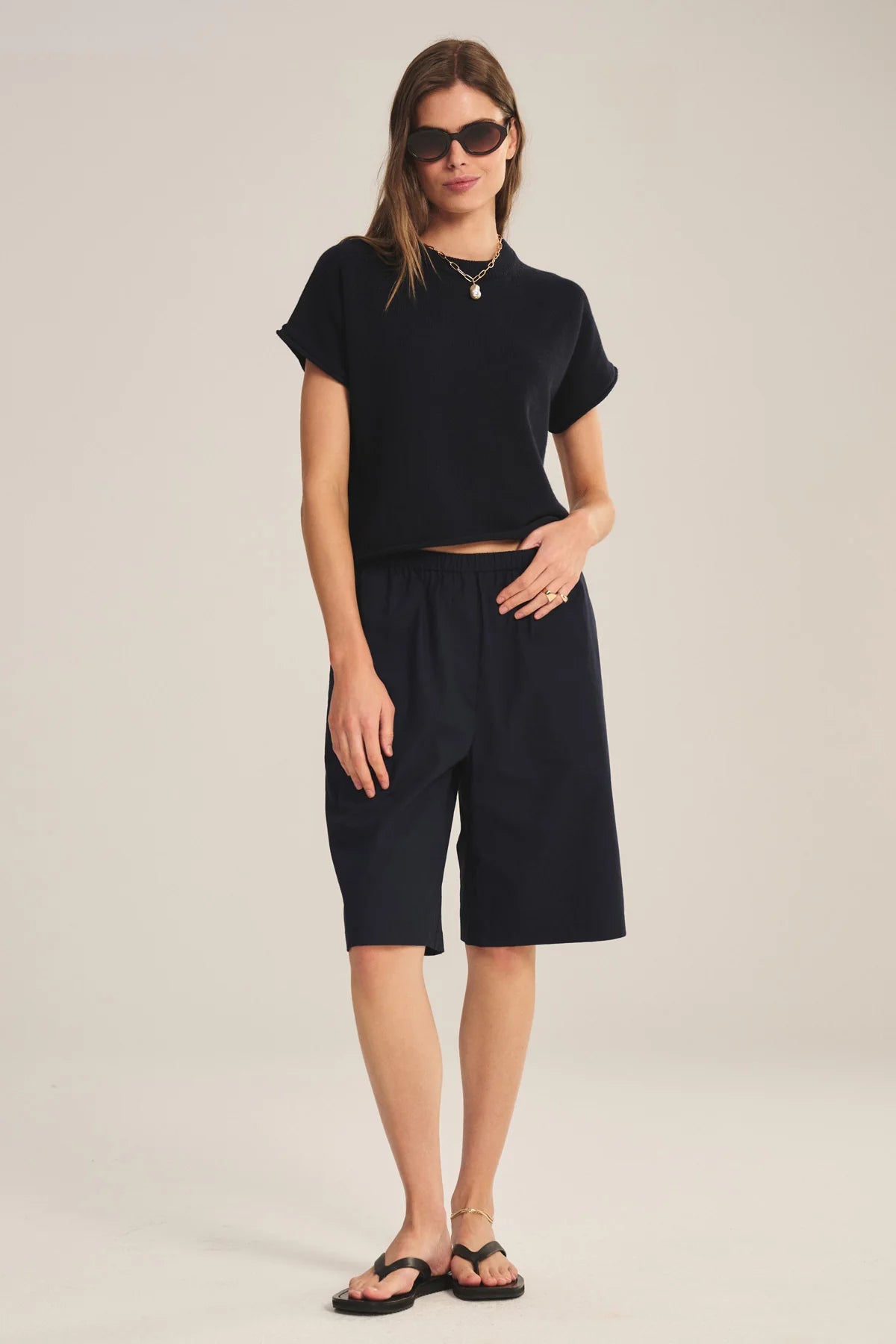 Woman wearing a black outfit with shorts on a plain background
