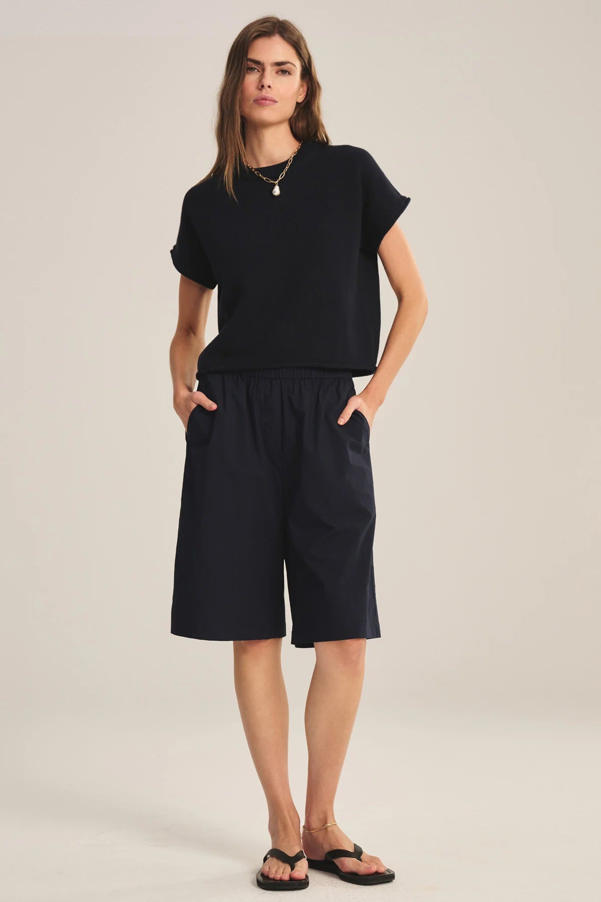 Woman wearing a black outfit with a top and shorts on a plain background
