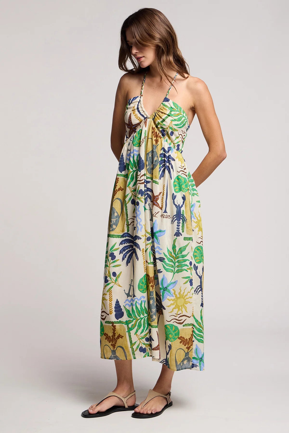 Woman wearing a tropical print dress on a plain background