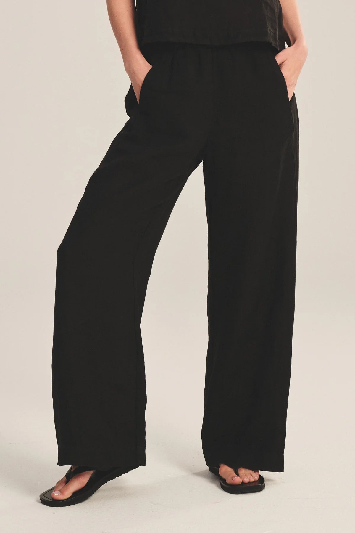 Person wearing black wide-leg pants on a plain background