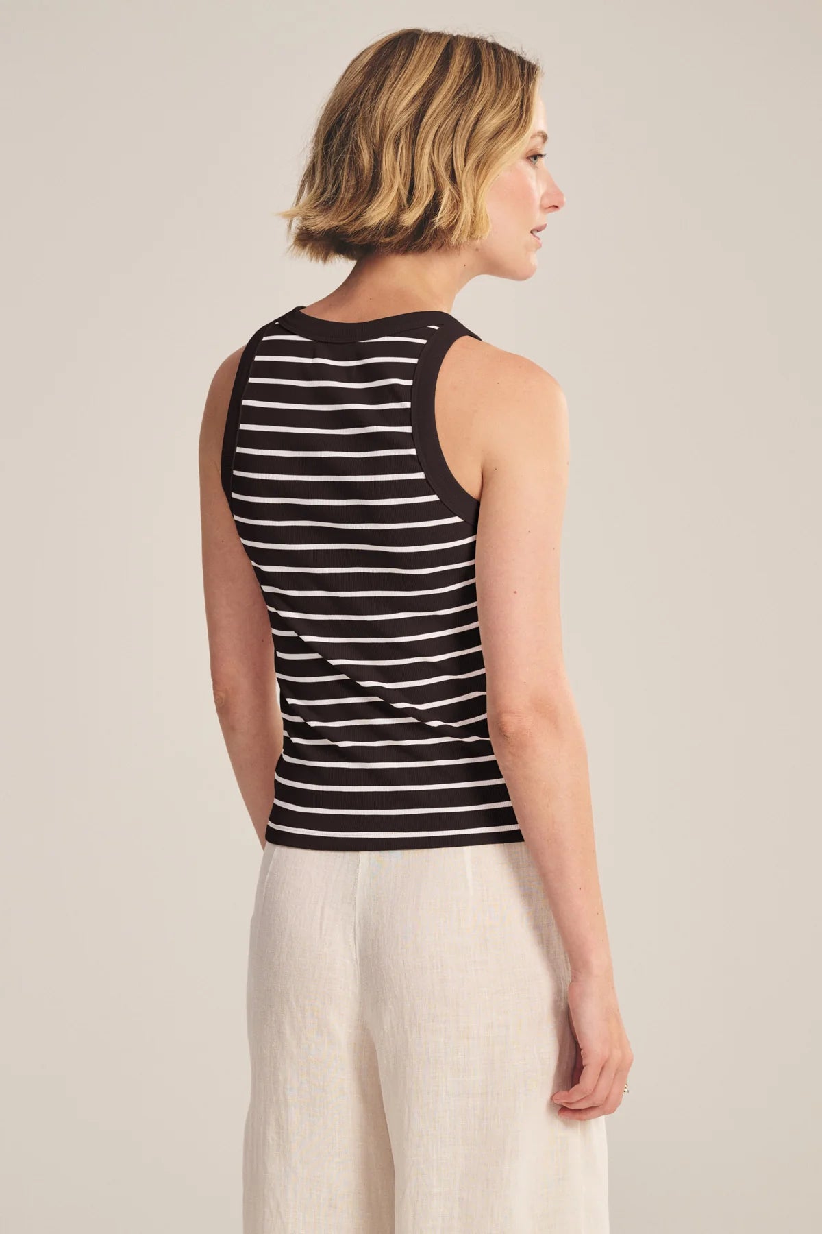 Woman wearing a black and white striped tank top against a plain background