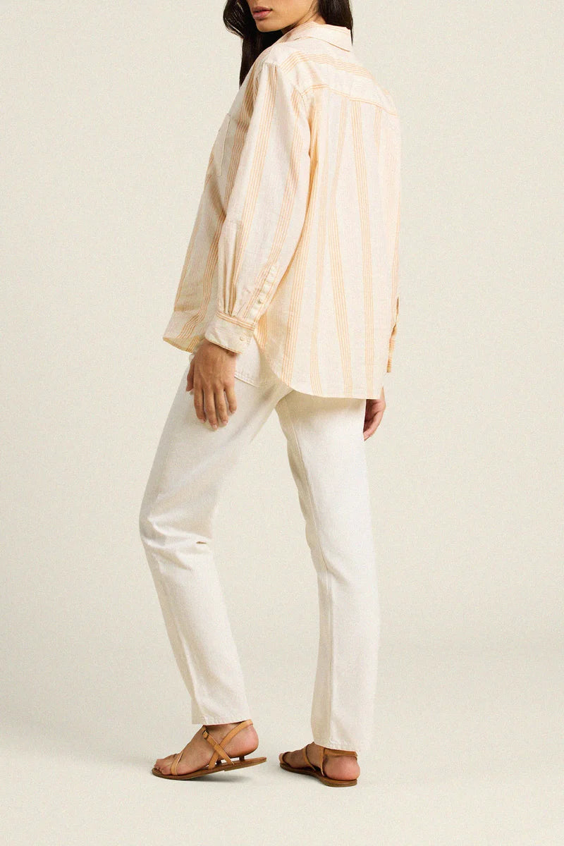 Person wearing a light-colored shirt and white pants on a plain background