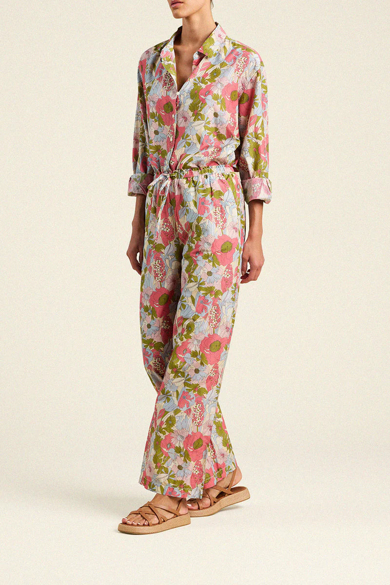 Person wearing a floral jumpsuit on a plain background