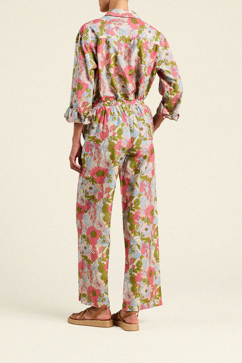 Person wearing a floral jumpsuit on a beige background