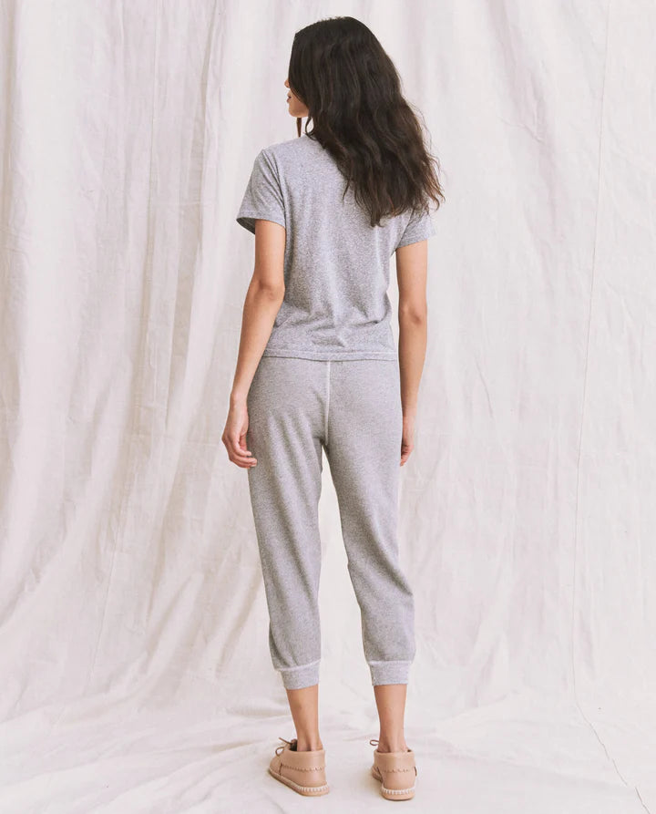 Woman wearing a gray outfit standing against a white curtain