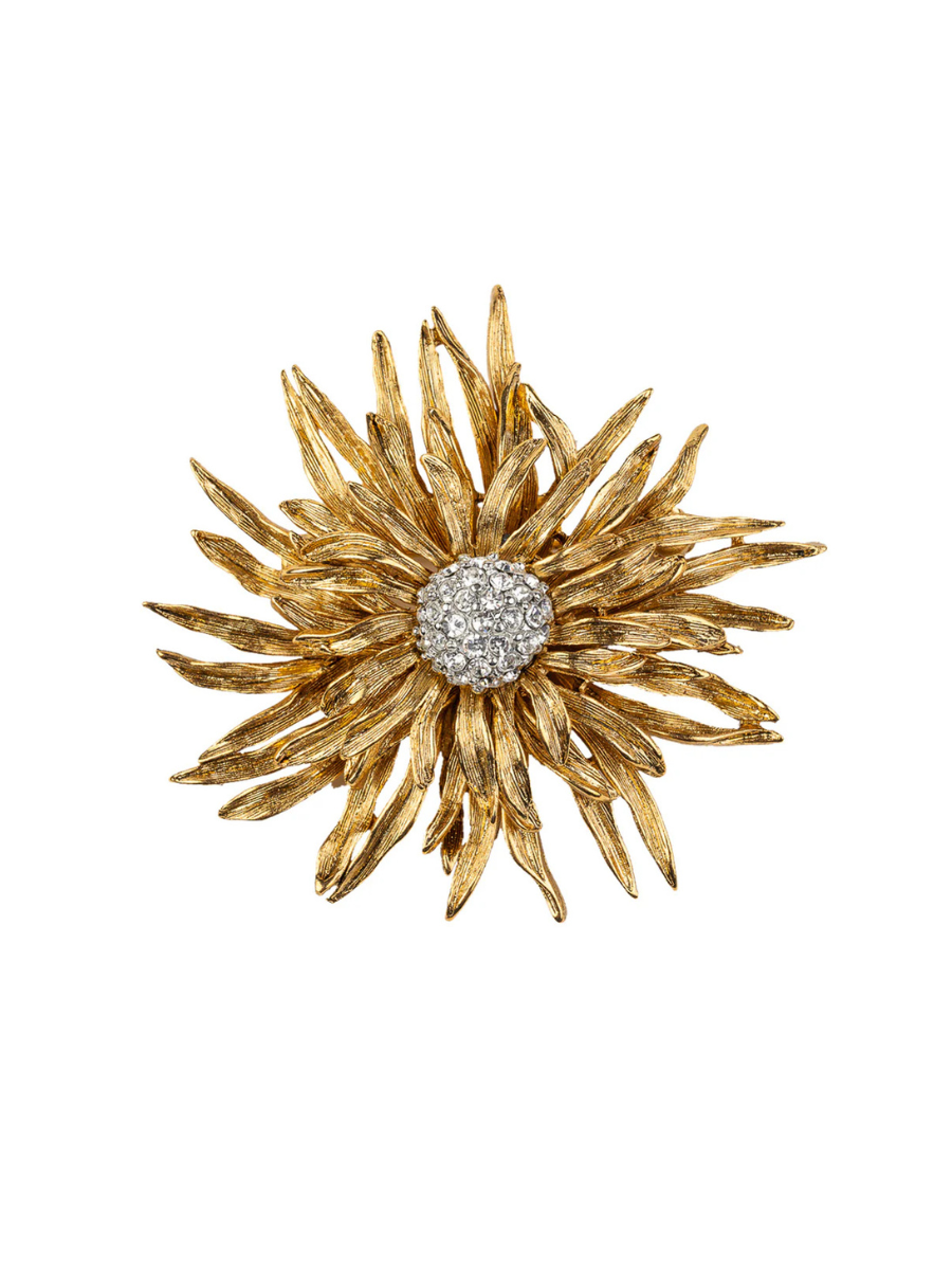 Gold flower-shaped brooch with a central gemstone on a white background