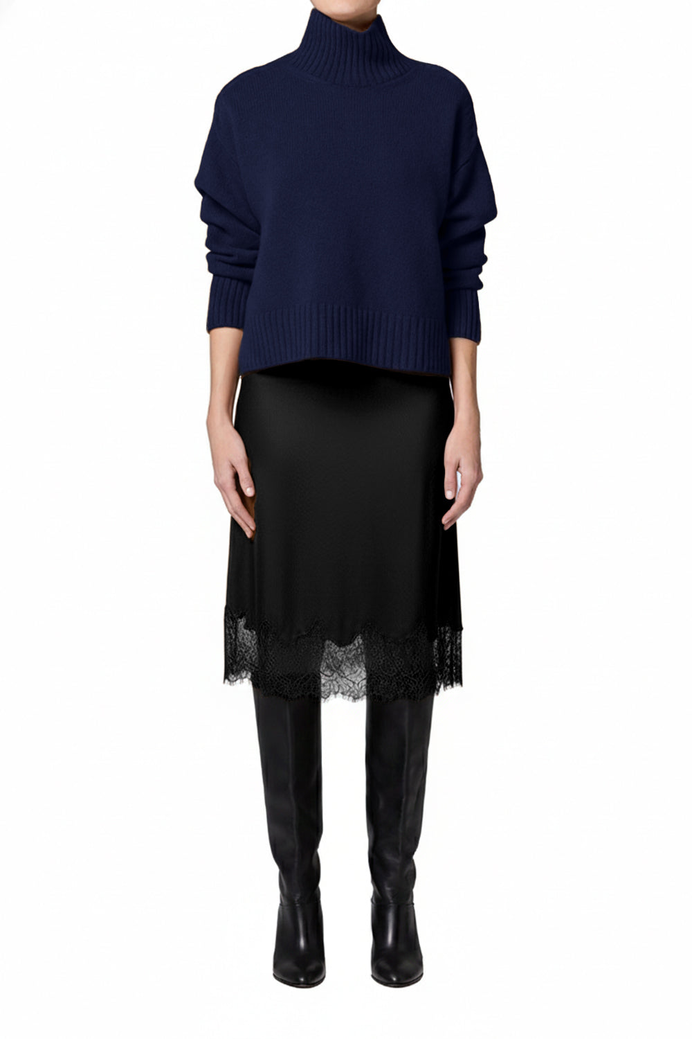 Person wearing a navy sweater and black skirt with sheer overlay on a white background