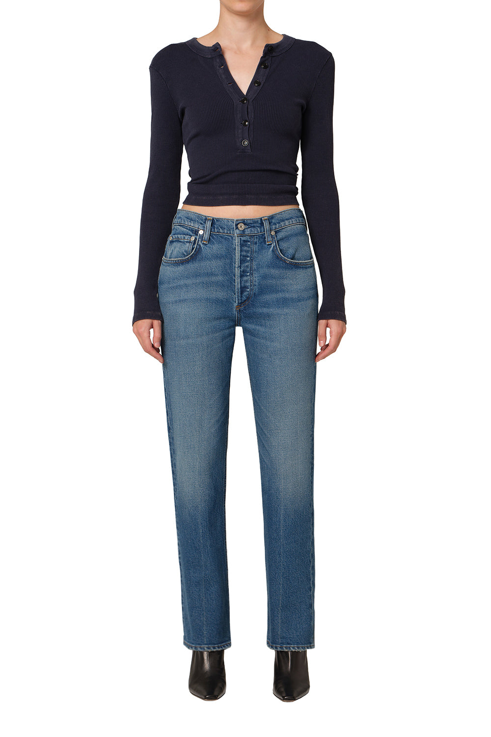 Person wearing a black long-sleeve top and blue jeans on a white background