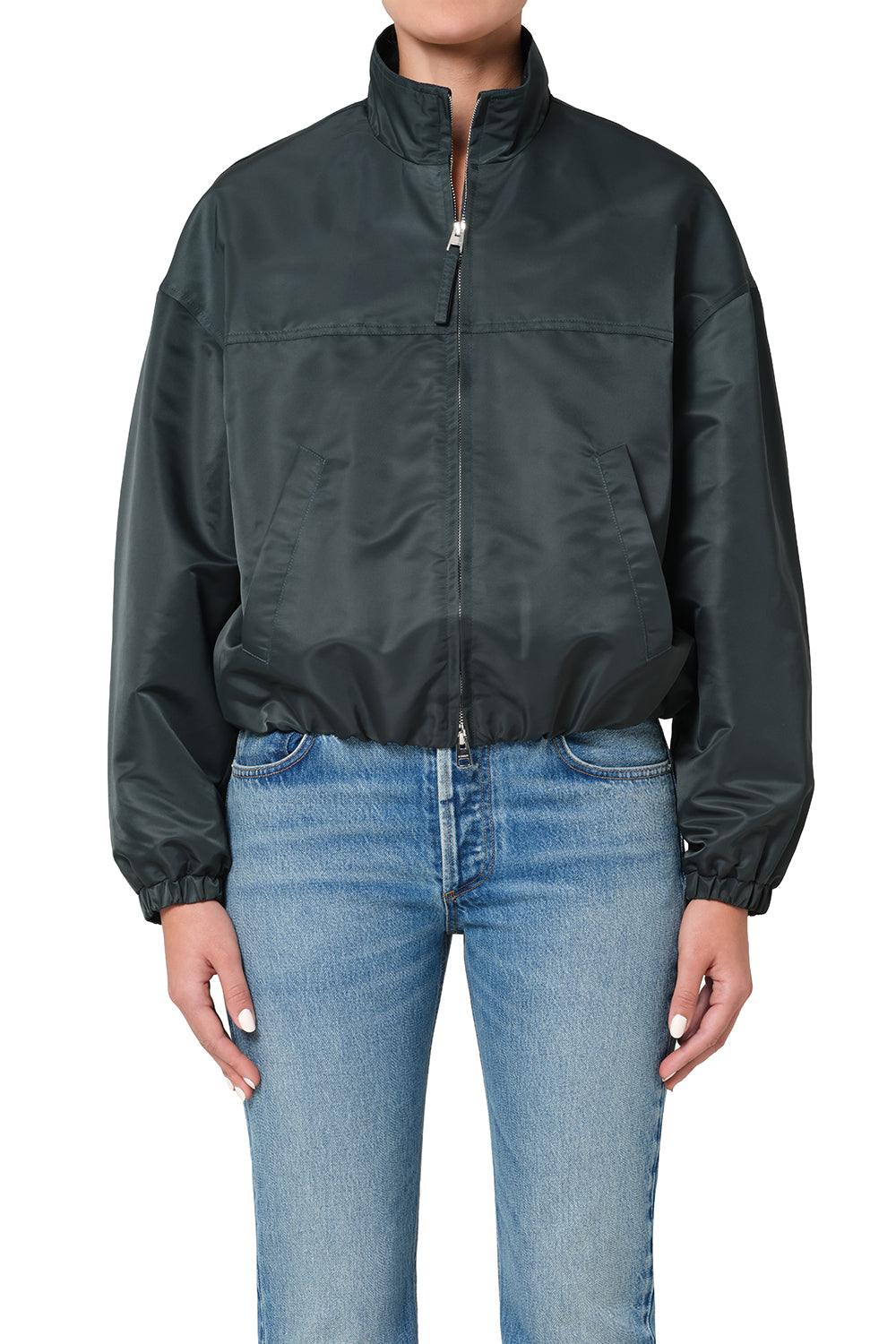 Person wearing a dark green jacket and light blue jeans on a white background