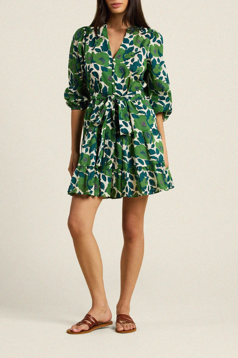 Woman wearing a green and white patterned dress on a plain background