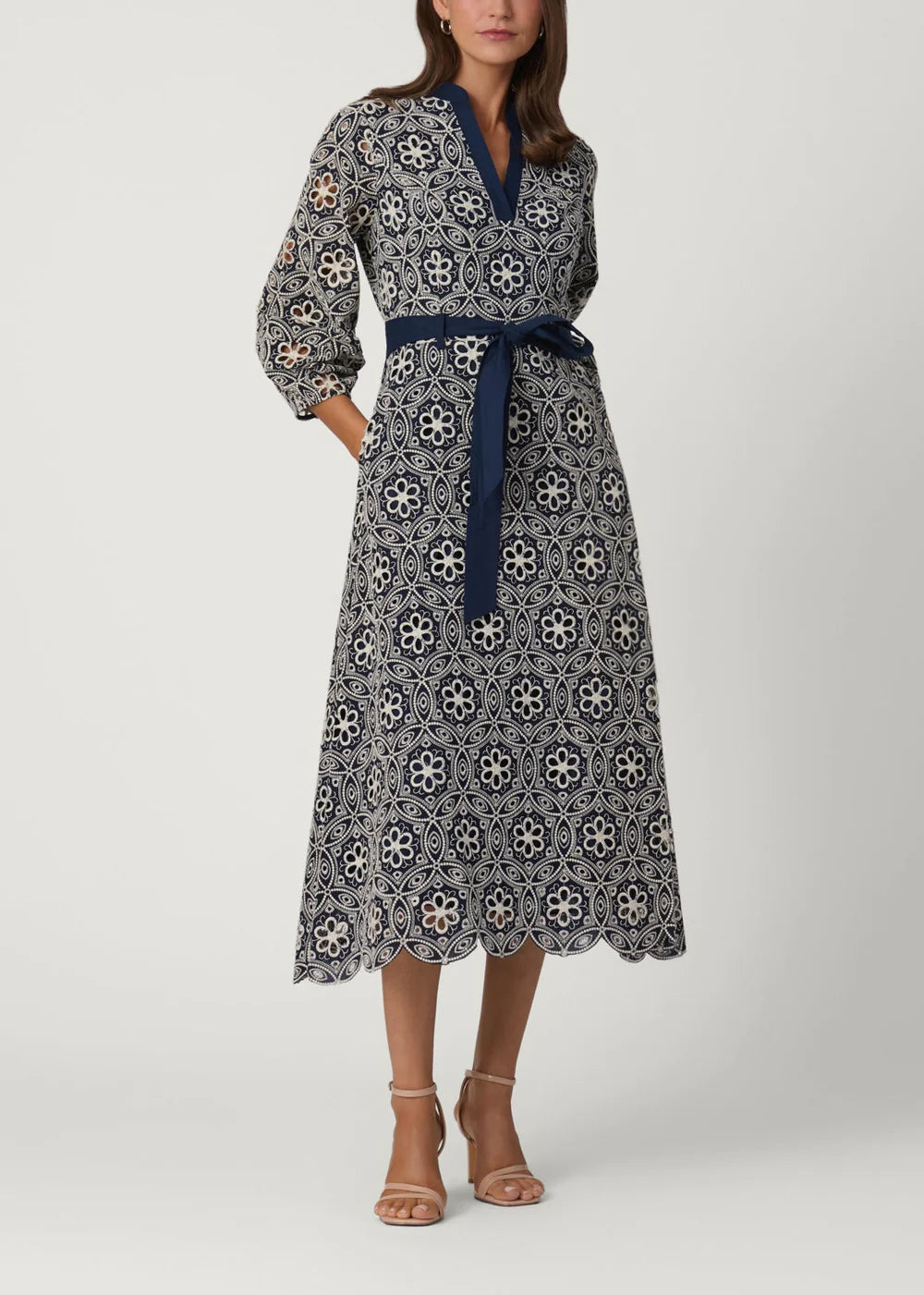 Woman wearing a patterned dress with a belt on a white background