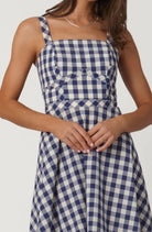 Woman wearing a blue and white checkered dress on a plain background