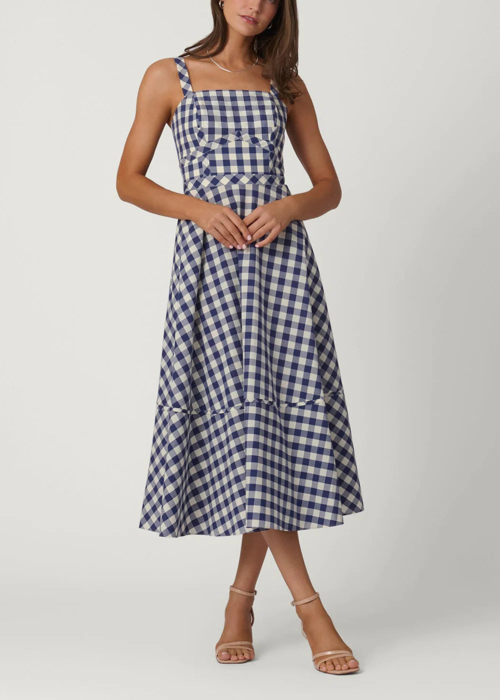 Woman wearing a blue and white checkered dress on a white background