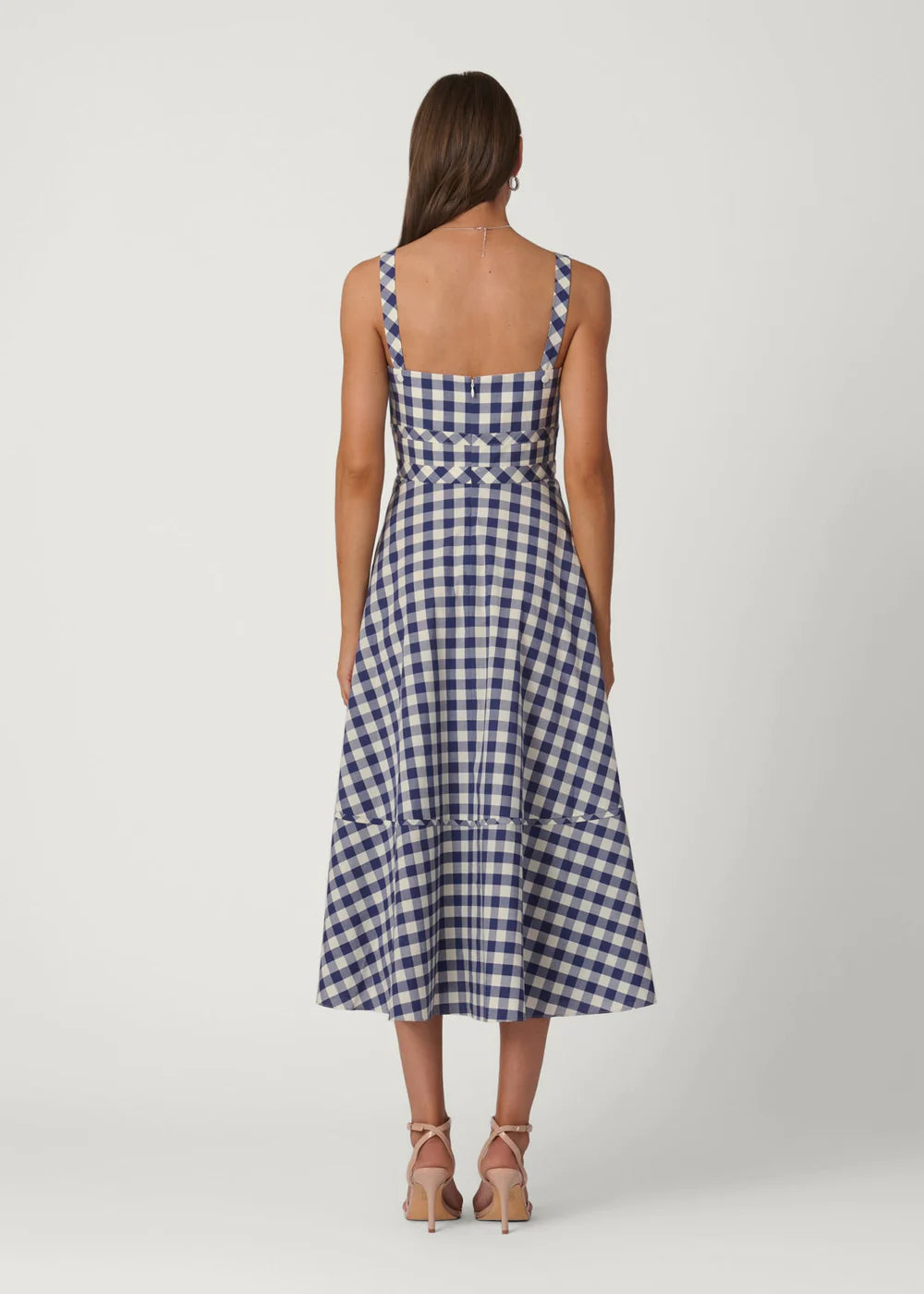 Woman wearing a blue and white checkered dress on a white background