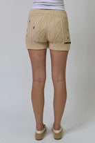 Beige cable knit shorts worn by a person on a white background