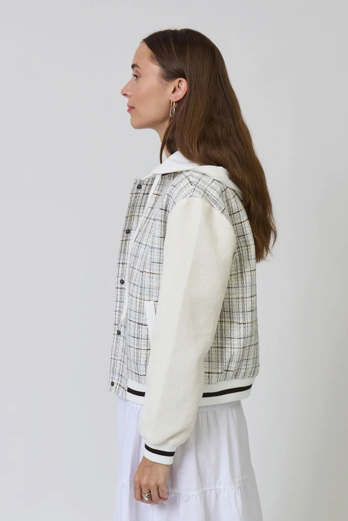 Woman wearing a checkered jacket over a white shirt with a plain background