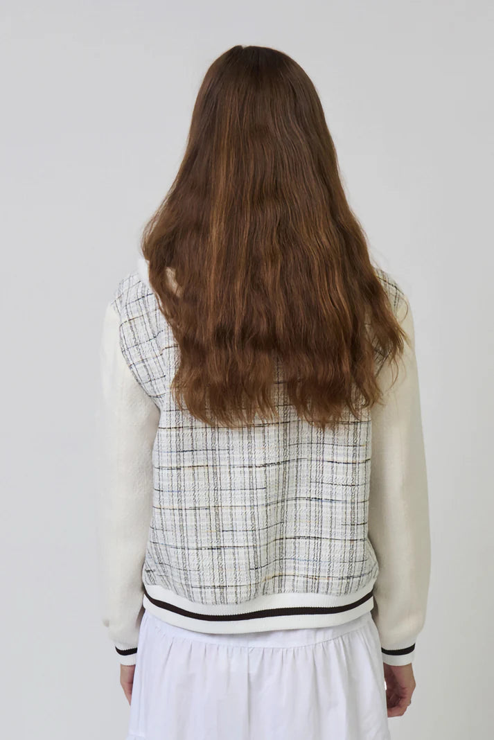 Person wearing a checkered vest over a white shirt with a plain background