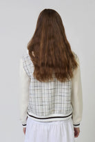 Person wearing a checkered vest over a white shirt with a plain background