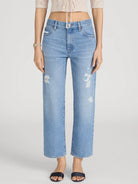 Person wearing light blue distressed jeans on a white background