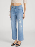 Light blue jeans with distressed details worn by a person on a white background