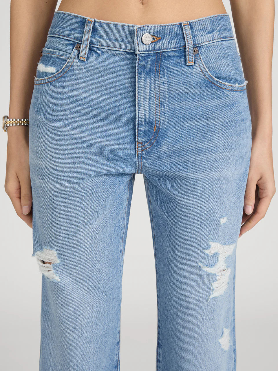 Light blue jeans with distressed details on a plain background