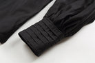 Close-up of a black sleeve with pleated cuffs on a white background
