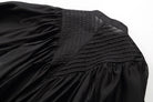 Close-up of a black skirt with pleated details on a white background
