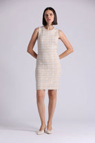 Woman wearing a sleeveless, knee-length dress with a subtle pattern on a plain background