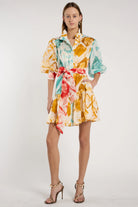 Model wearing a colorful floral dress on a white background