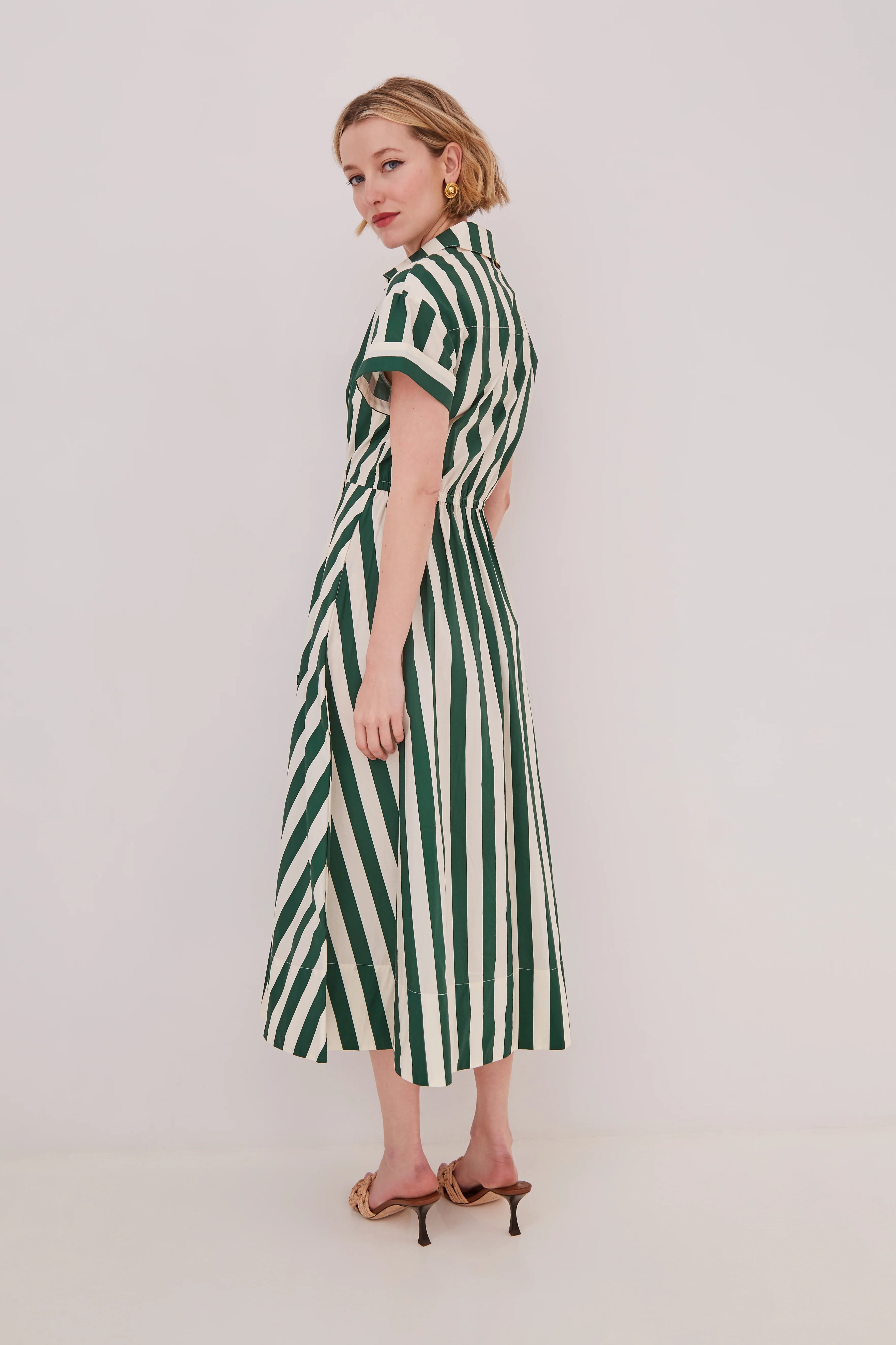 Woman wearing a green and white striped dress on a plain background