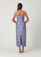 Woman wearing a strapless floral dress with a slit on a white background