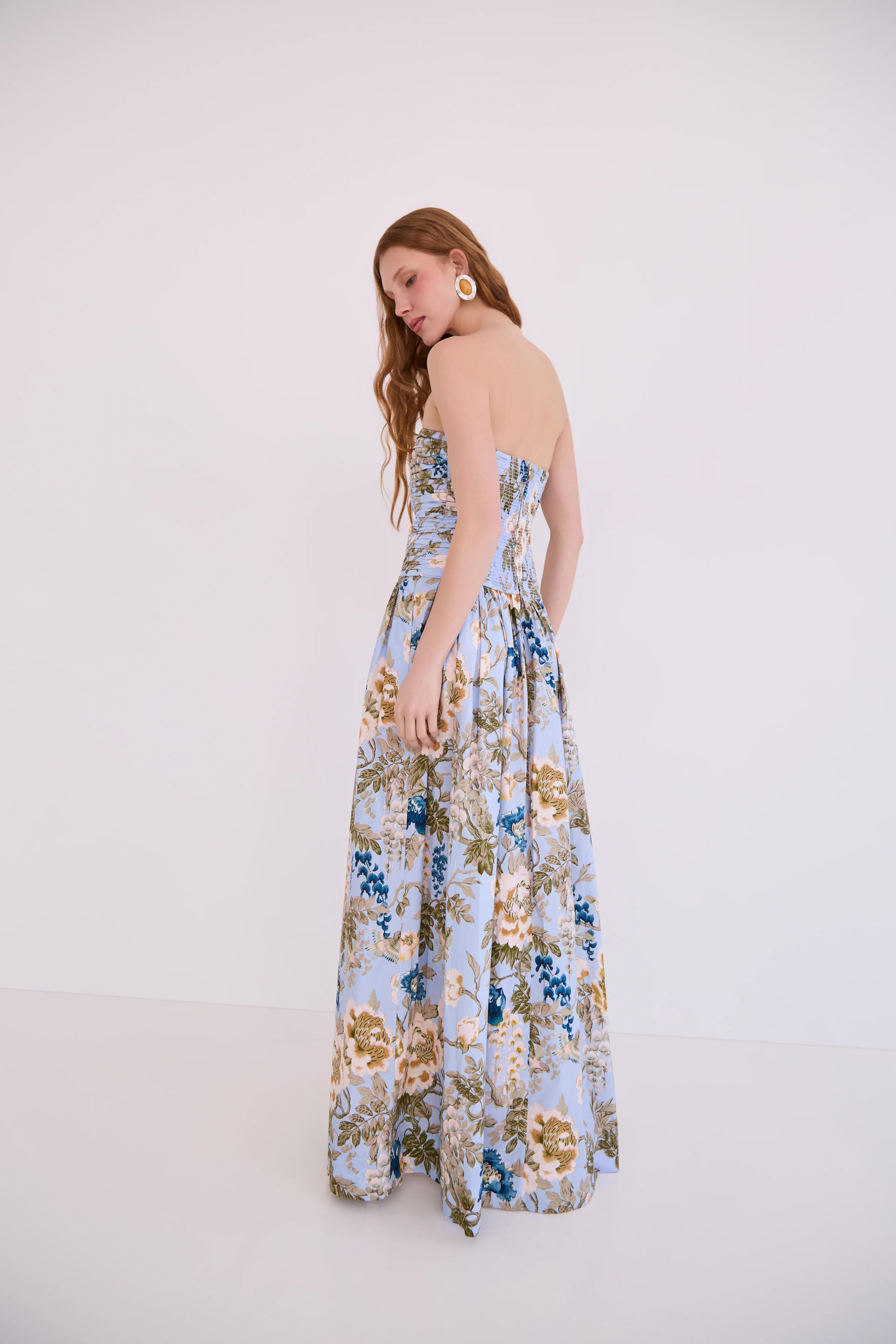 Woman wearing a floral strapless dress on a white background