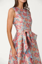 Woman wearing a sleeveless floral dress with a belt on a white background