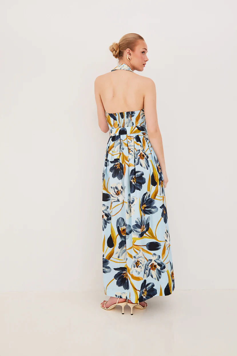 Woman wearing a floral strapless jumpsuit on a plain background