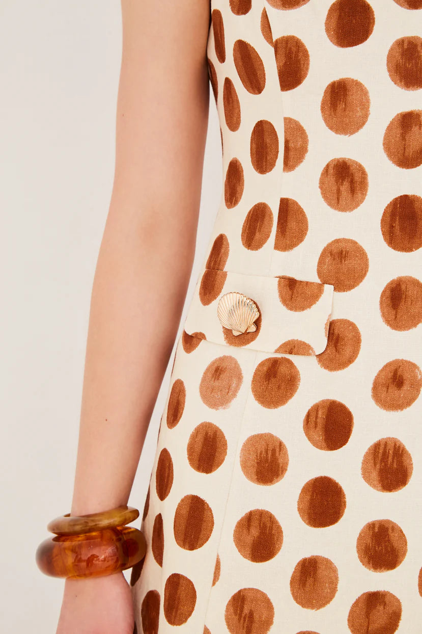 Close-up of a sleeveless dress with brown polka dot pattern on a plain background
