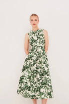 Woman wearing a sleeveless dress with green leaf pattern on a white background