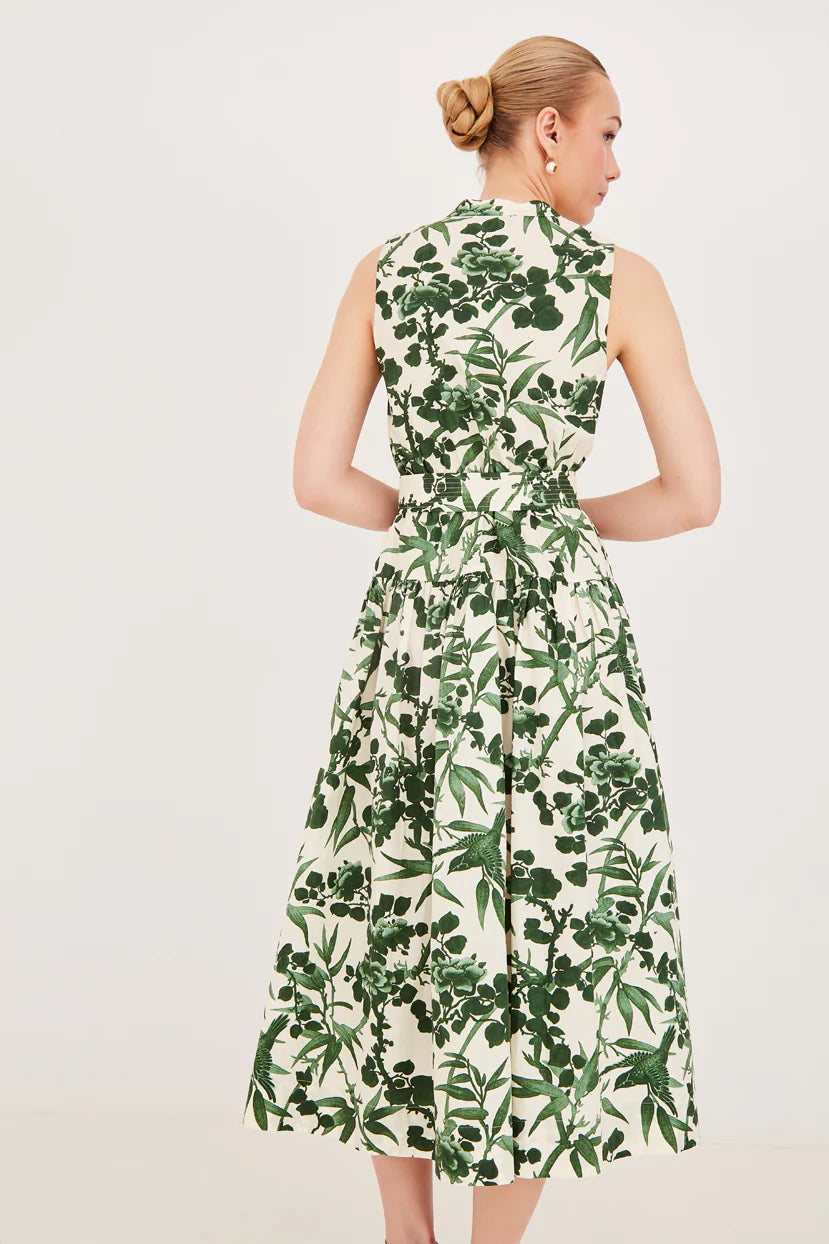 Woman wearing a sleeveless dress with green leaf pattern on a white background