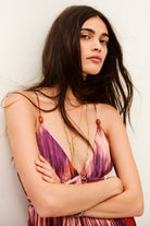 Woman wearing a colorful dress with floral patterns against a plain background