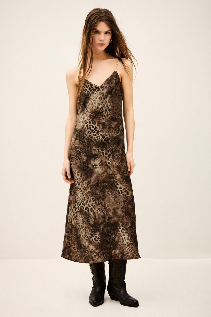 Woman wearing a patterned slip dress on a plain background