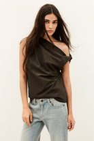 Woman wearing a black off-shoulder top and light blue jeans on a plain background