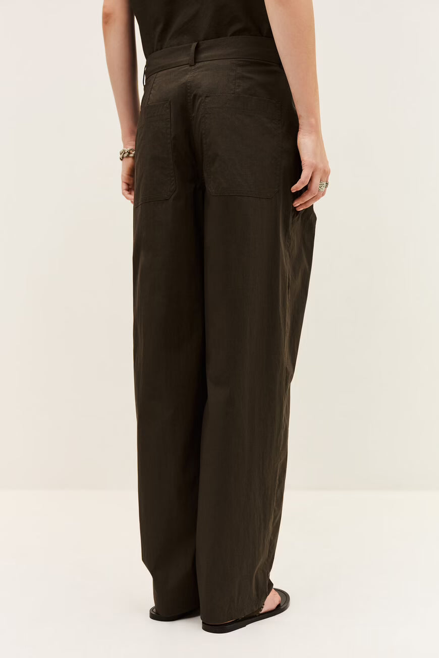 Person wearing dark brown wide-leg pants on a white background