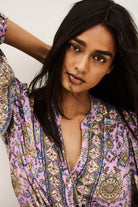 Woman wearing a colorful patterned top with a neutral background