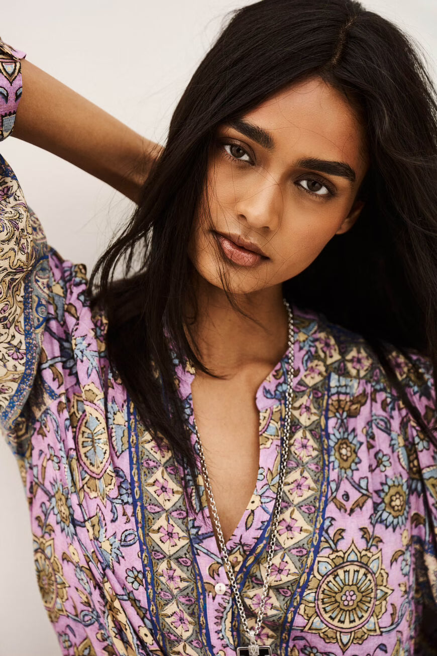Woman wearing a colorful patterned top with a neutral background