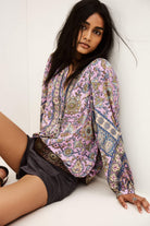 Woman wearing a patterned blouse sitting on a white surface