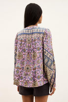 Person wearing a patterned blouse with a white background