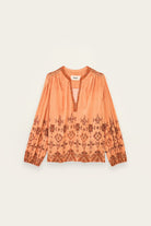 Orange blouse with pattern on a light beige background